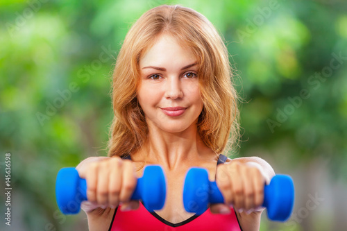 Active sporty woman doing morning exercises with dumbbells at home. Workout plan to get summer beach body. Healthy lifestyle, fitness exercises to keep fit, loss weight and shaping perfect slim body.
