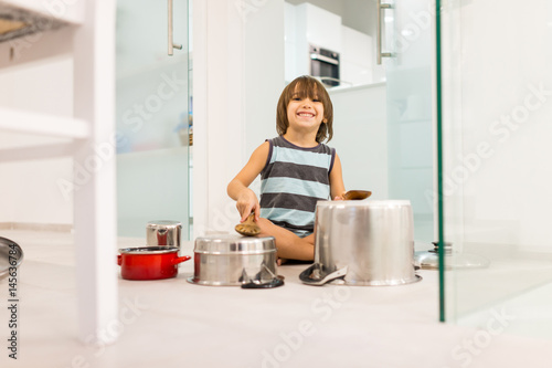 Happy kid at home playing with dishes as music instruments
