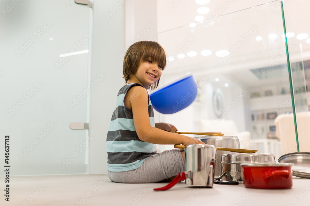 Happy kid at home playing with dishes as music instruments Happy kid at home playing with dishes as music instruments