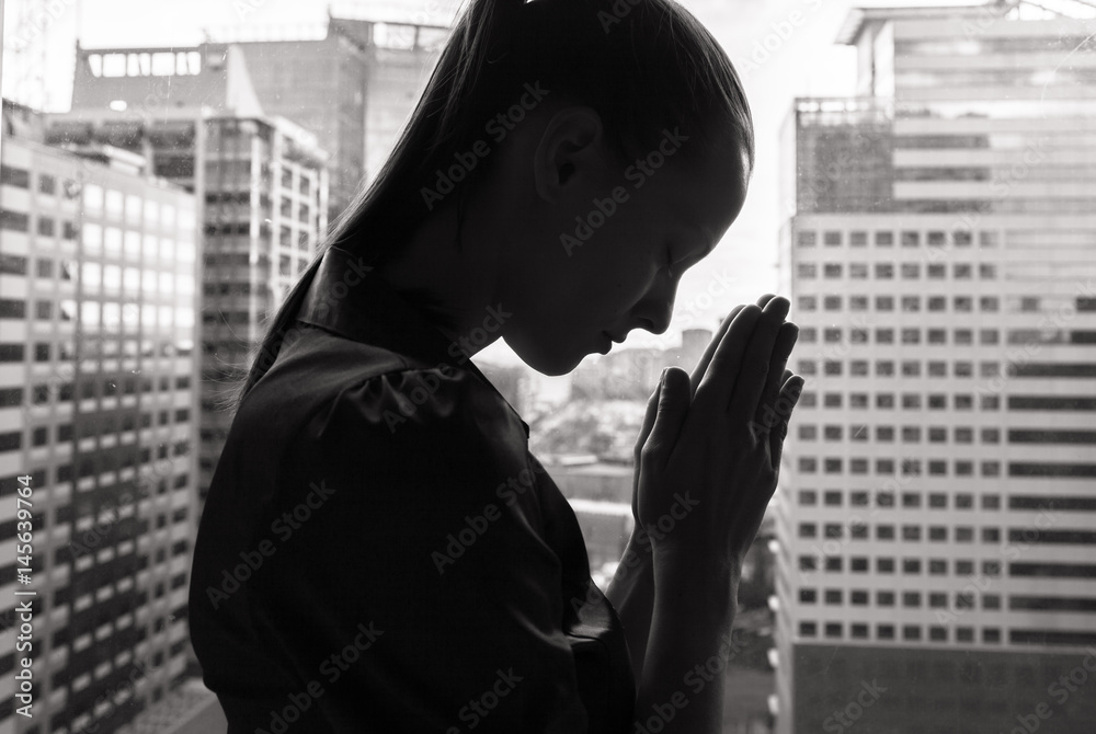 © kieferpix - Silhouette of woman praying in the city. © kieferpix - Silhouette of woman praying in the city.