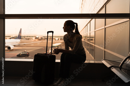 Flying and travel concept. Female traveler waiting at airport terminal.