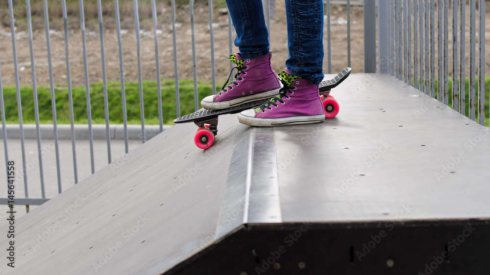 Girl's feet standing on the skateboard before jumping off the railing ...