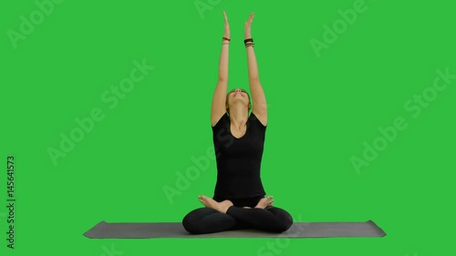 Young woman meditates while practicing yoga on a Green Screen, Chroma Key