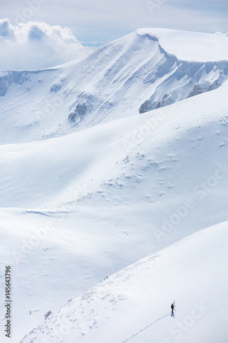 a skier is climbing the mountain ridge, snow, sunny day, in Carpathian mountains, Ukraine