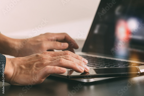 close up of businessman hand working with smart phone and laptop and digital tablet computer in modern office