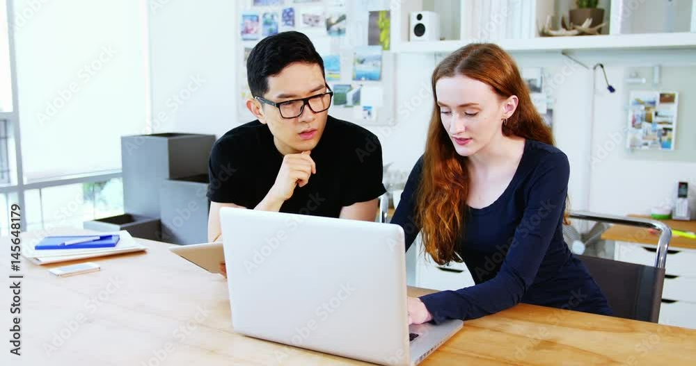 Business executives discussing over laptop Business executives discussing over laptop