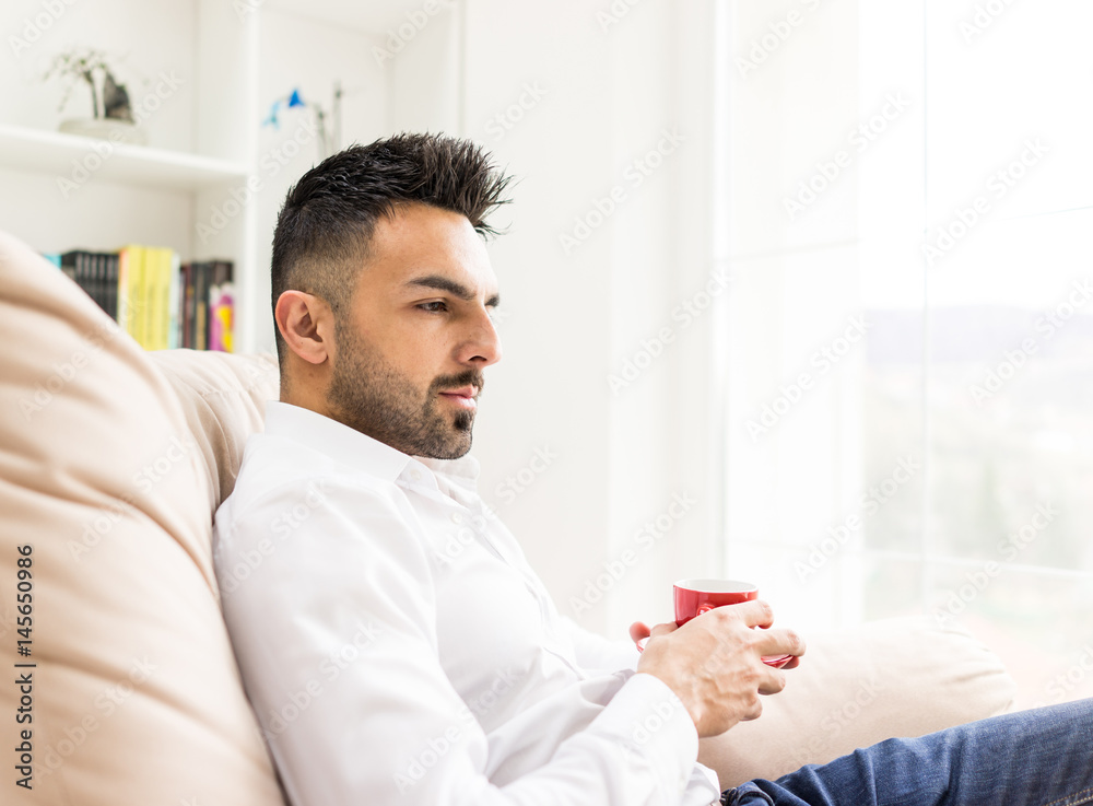 Young confident man drinking coffee at home