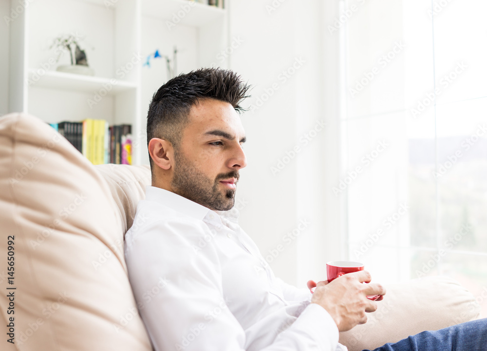 Young confident man drinking coffee at home