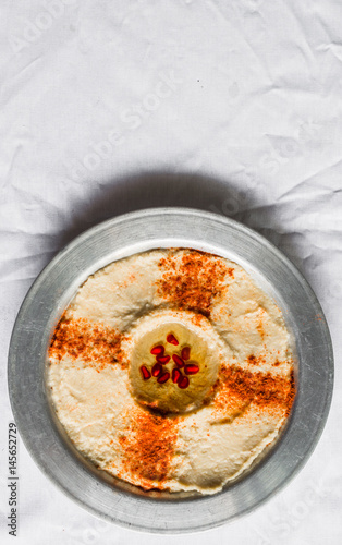 Hummus with paprika, olive oil, and pomegranate seeds against white background. Selective focus.