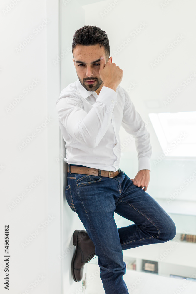 Attractive young man posing in white modern interior Attractive young man posing in white modern interior