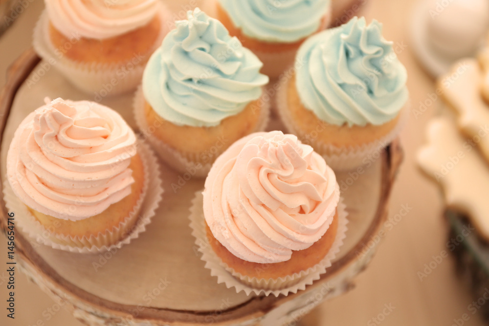 Wooden stand with tasty cupcakes on table, closeup Wooden stand with tasty cupcakes on table, closeup
