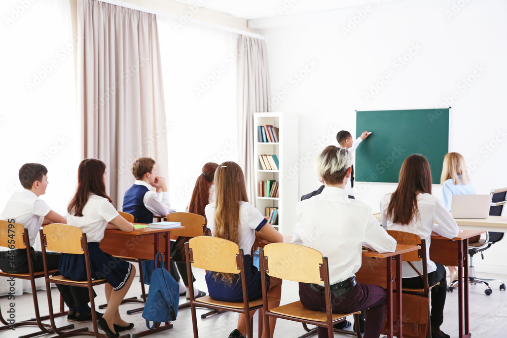 Schoolboy answering at blackboard in classroom Schoolboy answering at blackboard in classroom