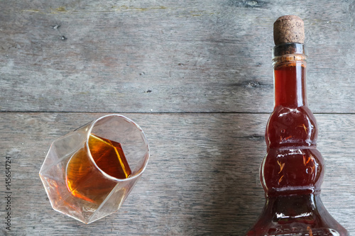 Local whiskey in a glass with bottle of herbal liquor.  photo