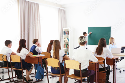 Schoolboy answering at blackboard in classroom