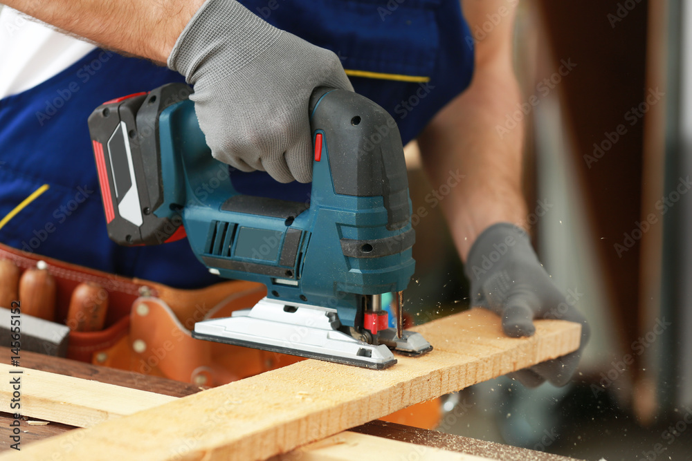 Young carpenter with electric fretsaw in workshop, closeup Young carpenter with electric fretsaw in workshop, closeup