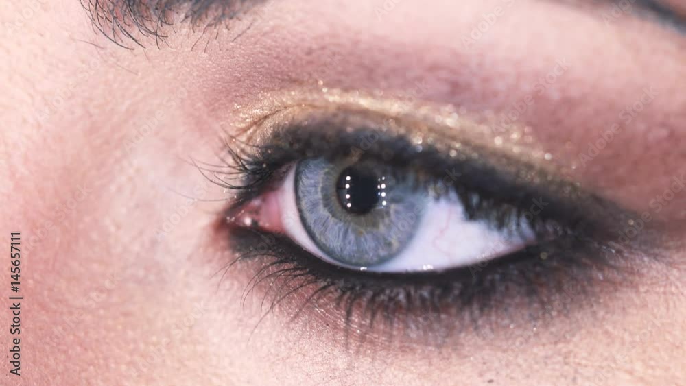 Woman's eye with gold eye shadow opens- macro Woman's eye with gold eye shadow opens- macro
