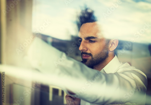 Double exposure confident attractive young man looking through the window glass