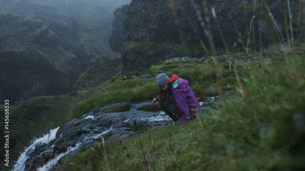 Woman sits at edge of waterfall, takes in view. Woman sits at edge of waterfall, takes in view.