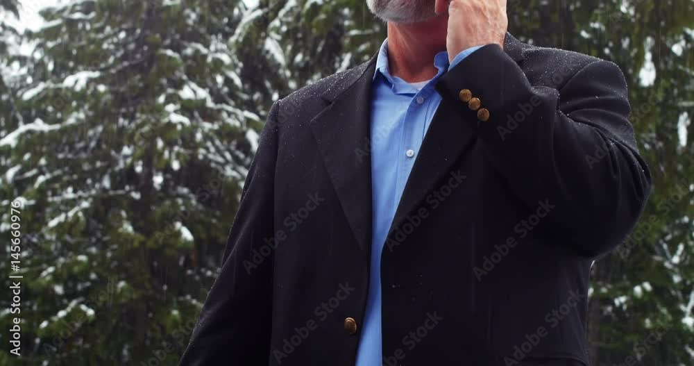 Man talking on the phone and charging the electric car on a snowy day Man talking on the phone and charging the electric car on a snowy day