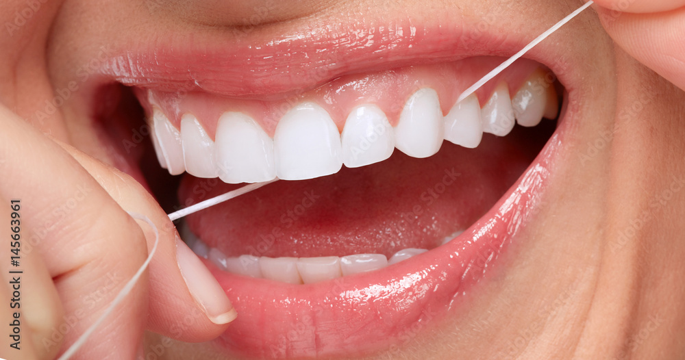 Obraz premium uśmiech kobiety z nicią dentystyczną