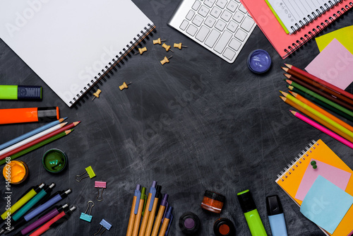 School stationery or office supplies on chalkboard background.
