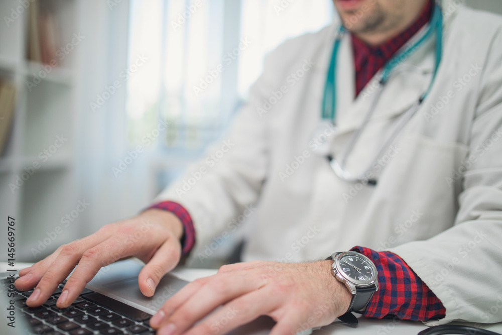 Cropped photo of doctor using laptop in his office Cropped photo of doctor using laptop in his office