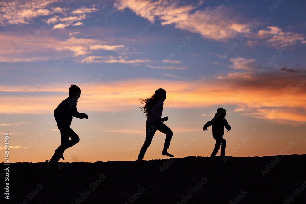 children running on the background of sunset sky