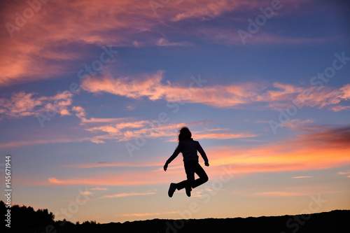 Girls jump on the sunset background