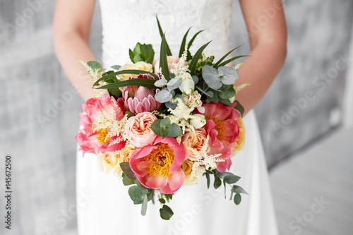 pink peony bouquet in hands of the bride