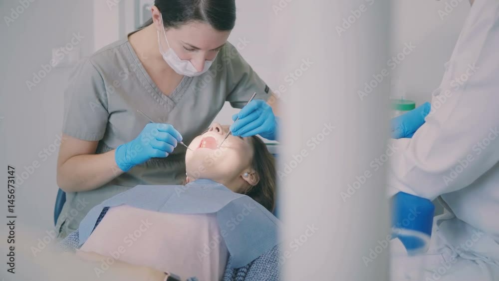 Young woman visiting the dentist office. Female sitting in dental chair while the doctor checking-up her mouth. Young woman visiting the dentist office. Female sitting in dental chair while the doctor checking-up her mouth.