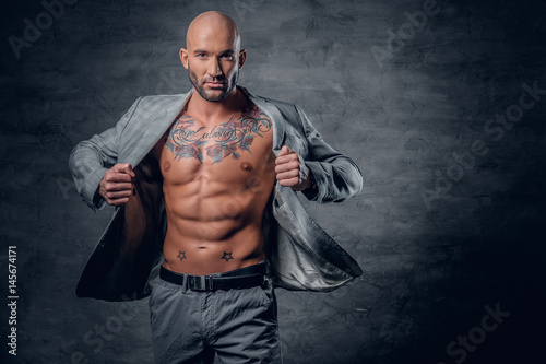 Fotografija Shaved head tattooed male dressed in a grey jacket on a naked torso