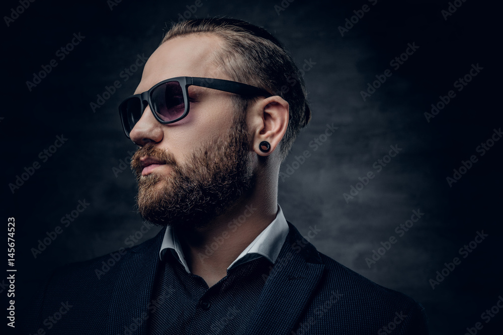 Stylish bearded male in sunglasses over dark grey background. Stylish bearded male in sunglasses over dark grey background.