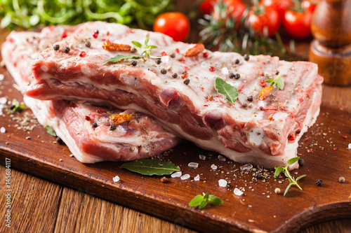 Raw pork ribs, on a plate sprinkled with spices.