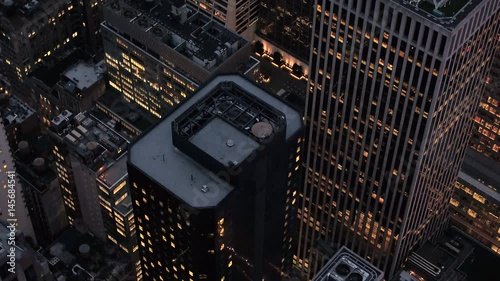 AERIAL HELI SHOT, CLOSE UP: Flying above the rooftops of skyscrapers, office buildings and blocks of flats in Midtown Manhattan, New York City in the early morning near Bryant Park and the 6th ave