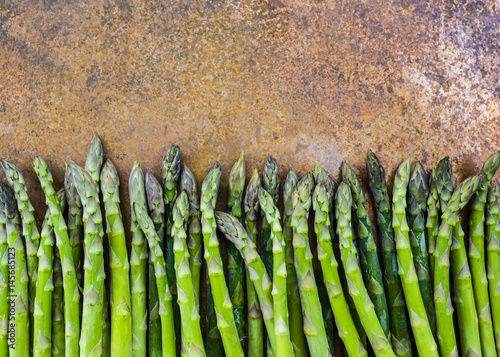 Fresh and raw green asparagus on a vintage background with space for text.