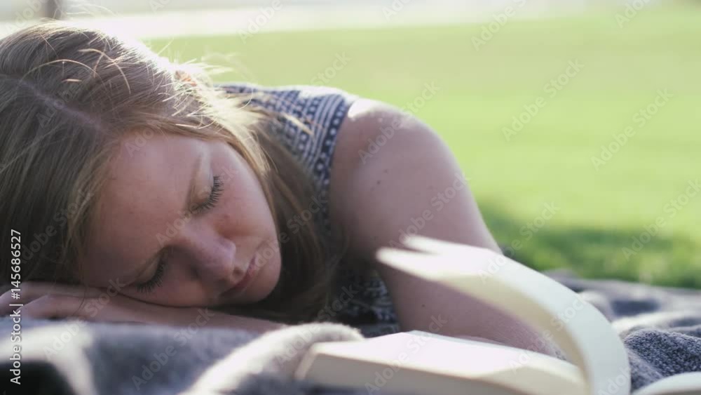 woman in park sleeping next to open book woman in park sleeping next to open book