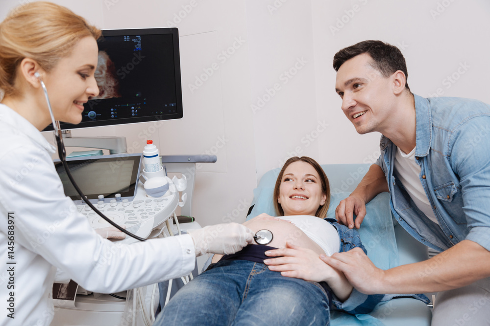Future father supporting pregnant wife in the sonography cabinet Future father supporting pregnant wife in the sonography cabinet