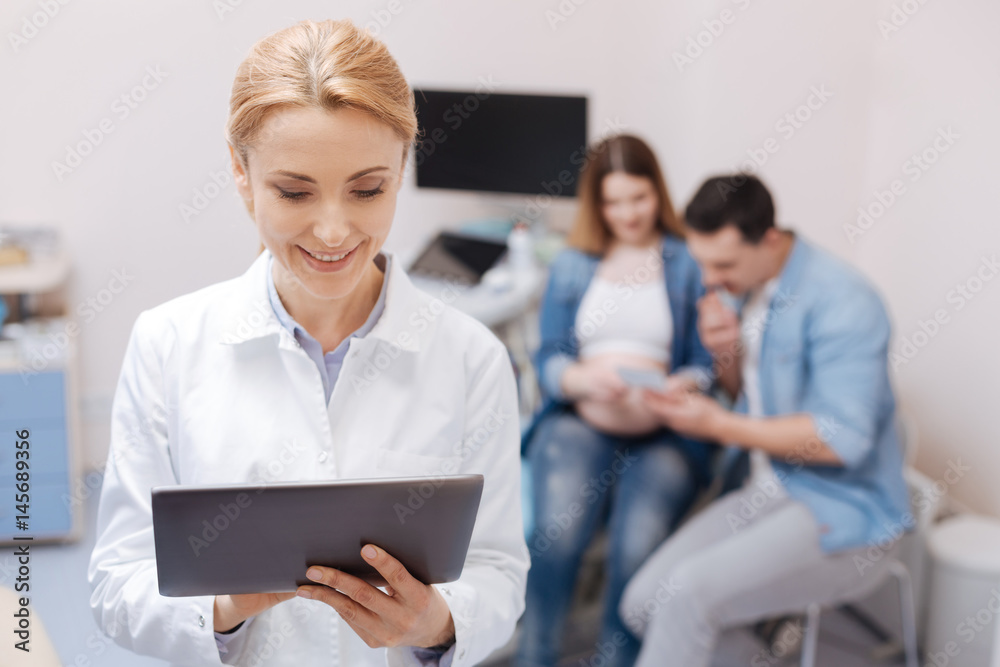 Amused doctor using tablet during appointment in the hospital Amused doctor using tablet during appointment in the hospital