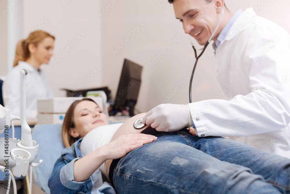 Upbeat medical specialists providing pregnant patient checkup at work Upbeat medical specialists providing pregnant patient checkup at work