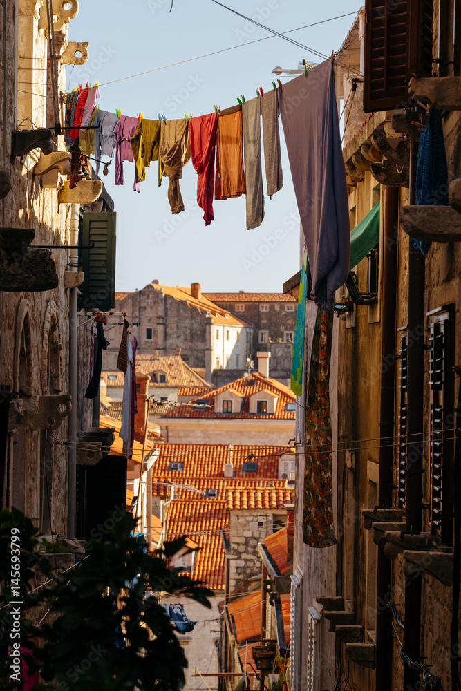 Naklejka premium Colorful linen dried on a rope in a narrow European street.