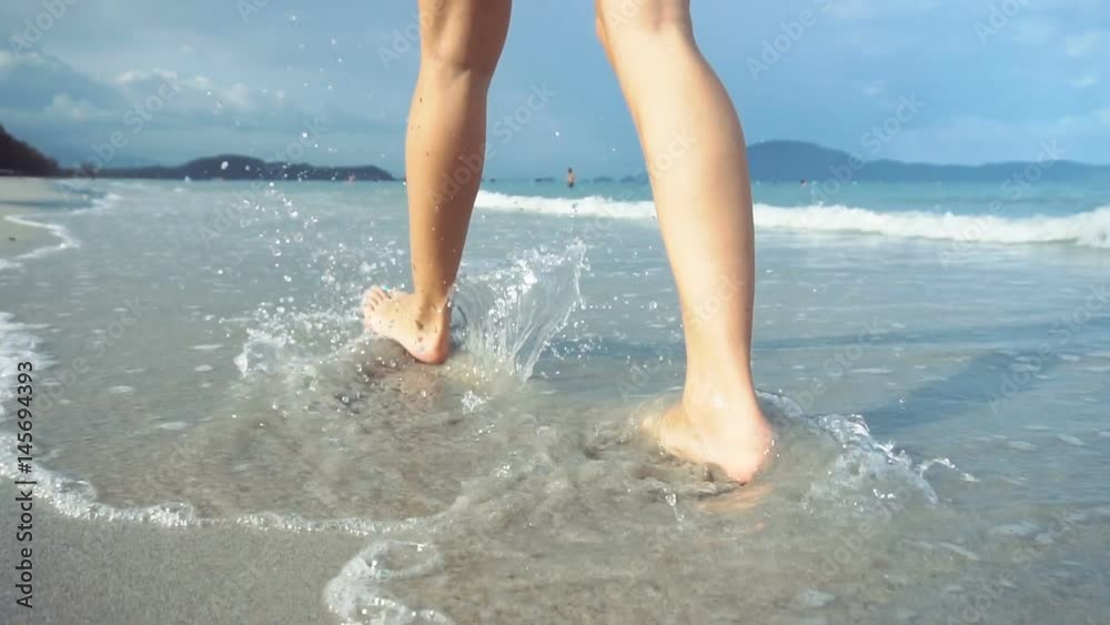 Woman walking on beach barefoot at sunset. Female strolling on sand near sea. Woman walking on beach barefoot at sunset. Female strolling on sand near sea.