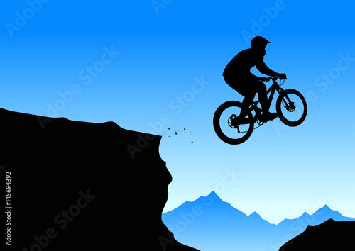 Silhouette of a biker jumping from mountain ledge