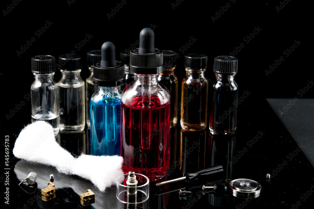 Electronic cigarette liquids with equipment on black background Electronic cigarette liquids with equipment on black background