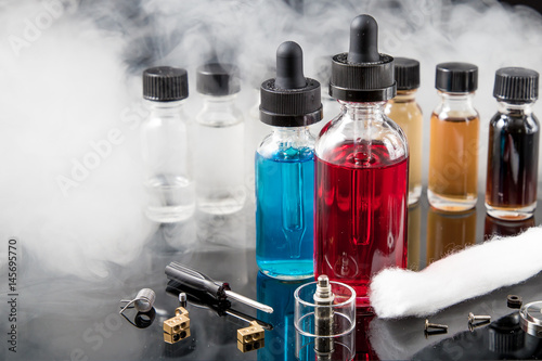 Electronic cigarette liquids with smoke on black background