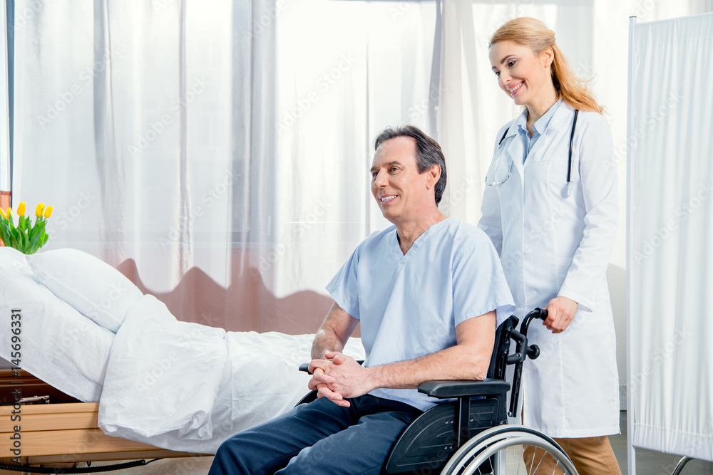 Obraz premium elderly man sitting in wheelchair and doctor standing near him in hospital