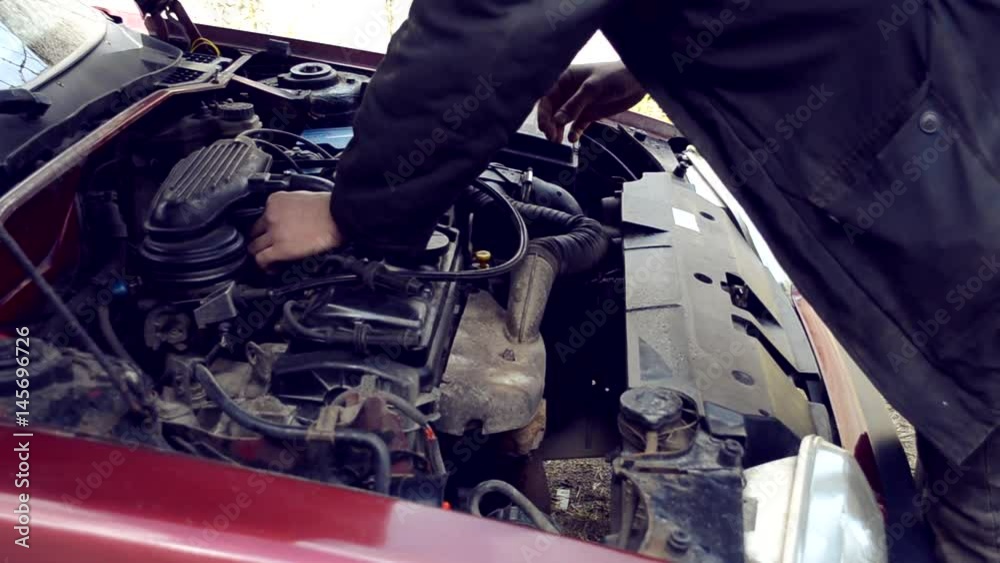 Man is repairing the engine in the car