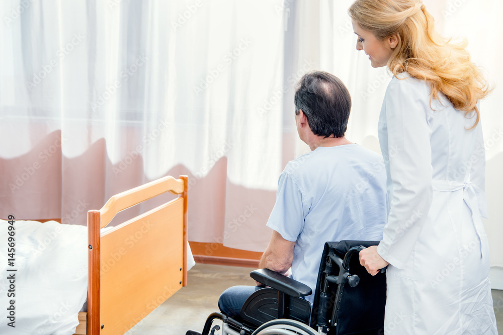 elderly man sitting in wheelchair and doctor standing near him in hospital elderly man sitting in wheelchair and doctor standing near him in hospital