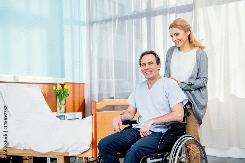 wheelchair man with wife near by in hospital chamber