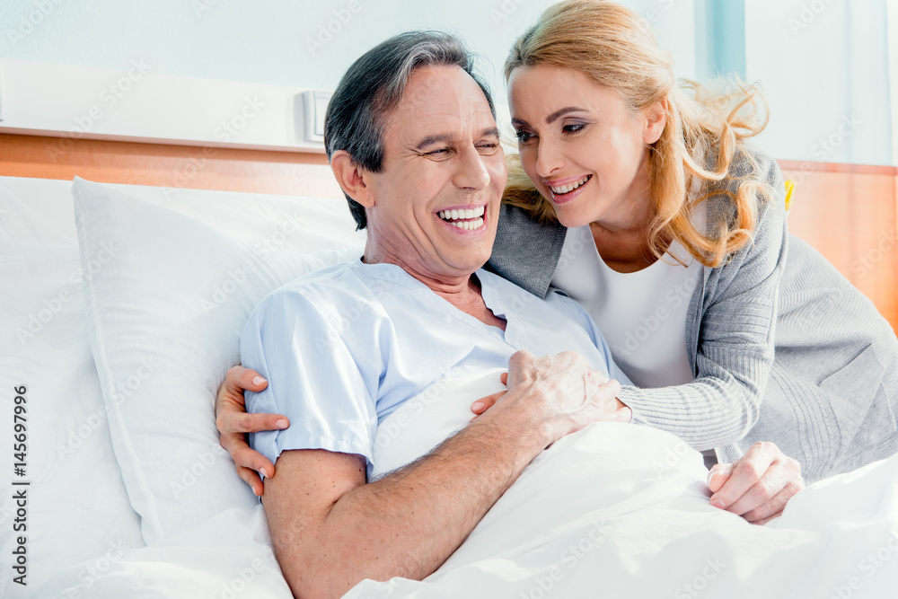 portrait of happy wife visiting elderly husband in hospital
