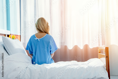 back view of woman sitting on bed in hospital chamber